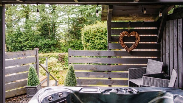 An outdoor patio with a wooden bench, a heart-shaped decoration, and a hot tub. - Squirrel Bank, with a hot tub & parking (Bowness-on-Windermere)