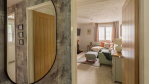 A room with a wooden door, a bed with pillows, a desk with a lamp, and a mirror on the wall. - Squirrel Bank, with a hot tub & parking (Bowness-on-Windermere)