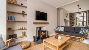 Un salon chaleureux avec une cheminée, un canapé, une table basse et des étagères remplies de livres et d’objets décoratifs.
