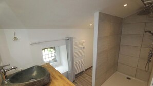Un baño moderno con lavamanos de piedra, ducha y ventana que proporciona luz natural.