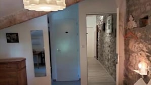 Un dormitorio con una cama, un aparador de madera, una lámpara colgante y una pared de piedra.