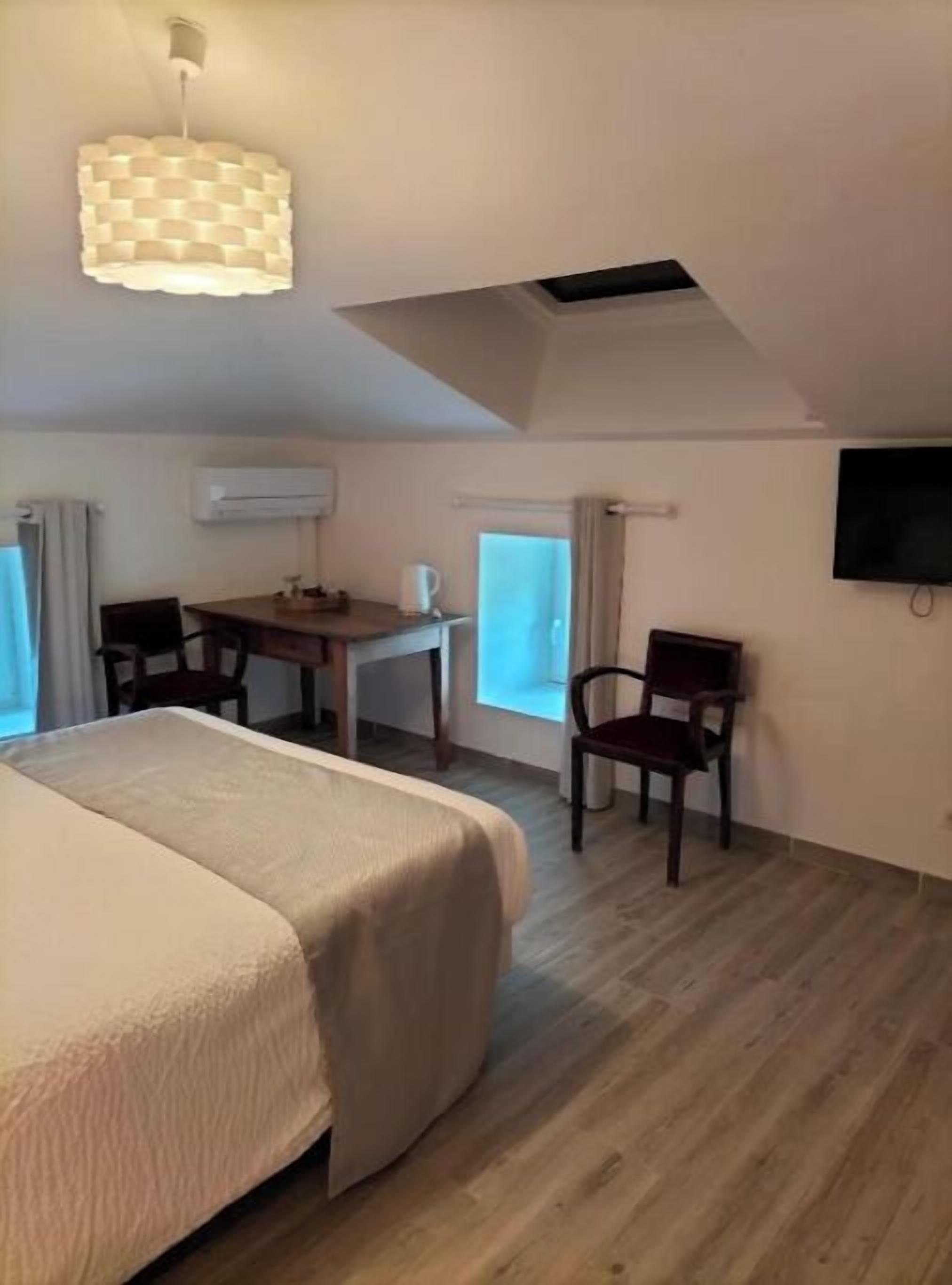 Ein Hotelzimmer mit einem großen Bett, einem Schreibtisch mit Stuhl, einem Fernseher und einem Fenster.