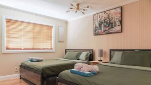 A hotel room with two single beds, a window with blinds, a painting on the wall, and a ceiling light fixture. - Private house with Pool (Las Vegas)