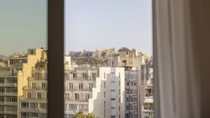 Vista a través de una ventana que muestra un paisaje urbano con varios edificios, incluyendo una estructura destacada en la cima de una colina.
