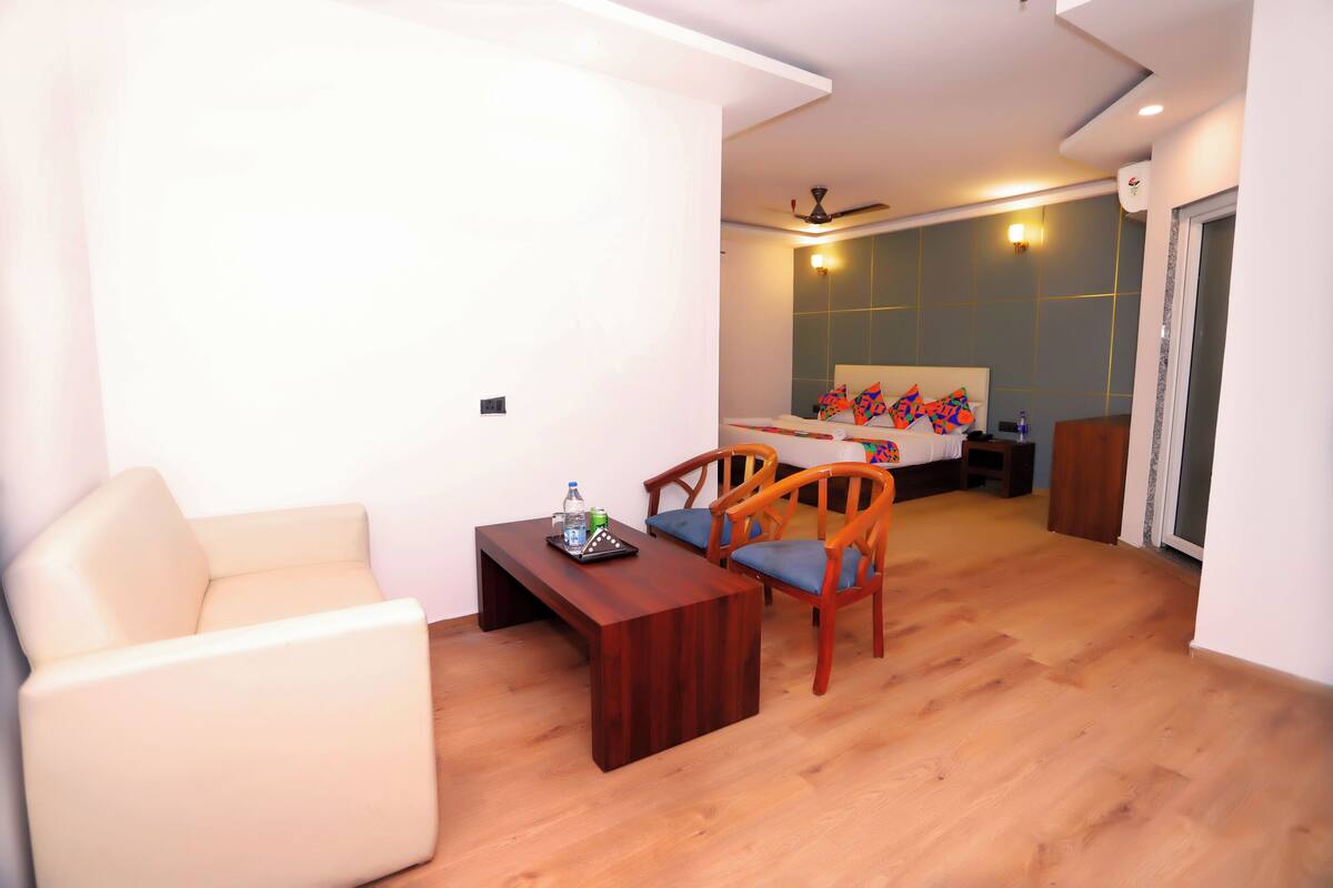 Ein modernes Hotelzimmer mit Holzboden, einer Couch, einem Holztisch und einem Bett mit bunten Kissen.