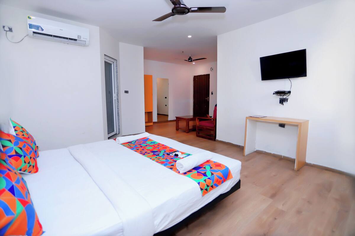 Ein Hotelzimmer mit Bett, Schreibtisch, Fernseher und Klimaanlage.