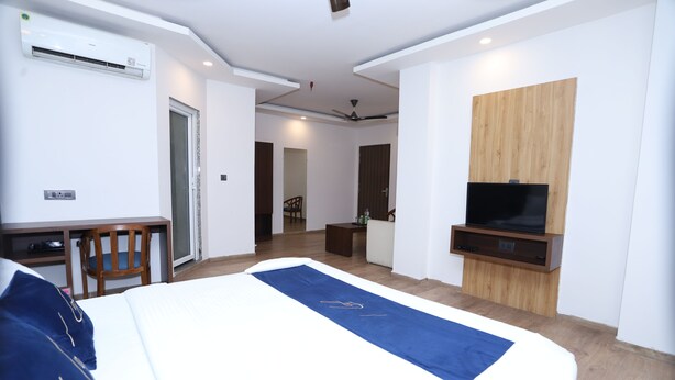 A hotel room with a bed, a desk, a chair, a TV, and a wooden panel wall. - Hotel Core One Bliss  (Noida)