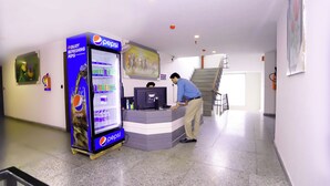 A Pepsi vending machine and a counter with a computer in a lobby area. - Hotel Core One Bliss  (Noida)