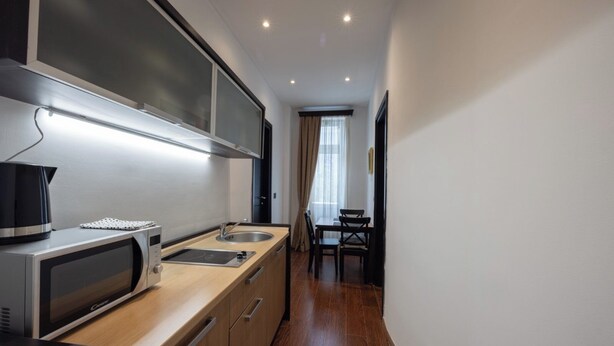 Cocina compacta con microondas, hervidor, pileta y comedor con mesa y sillas.