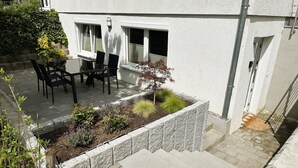 A patio with a table and chairs, a small garden bed, and a stone staircase leading to a door. - Rottweiler Ferienwohnung - Moderne Ferienwohnung mit Nähe zum Wasserturm (Rottweil)