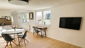 A modern kitchen with wooden cabinets, a white countertop, and a hanging pot rack. - Rottweiler Ferienwohnung - Moderne Ferienwohnung mit Nähe zum Wasserturm (Rottweil)