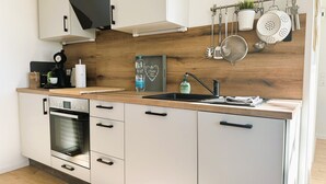 A modern kitchen with a Bosch oven, a sink, and a wooden backsplash. - Rottweiler Ferienwohnung - Moderne Ferienwohnung mit Nähe zum Wasserturm (Rottweil)