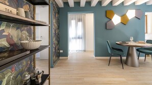 A modern dining area with a round table, teal walls, and a wooden floor. - The Green Jungle by Wonderful Italy (Venecia)