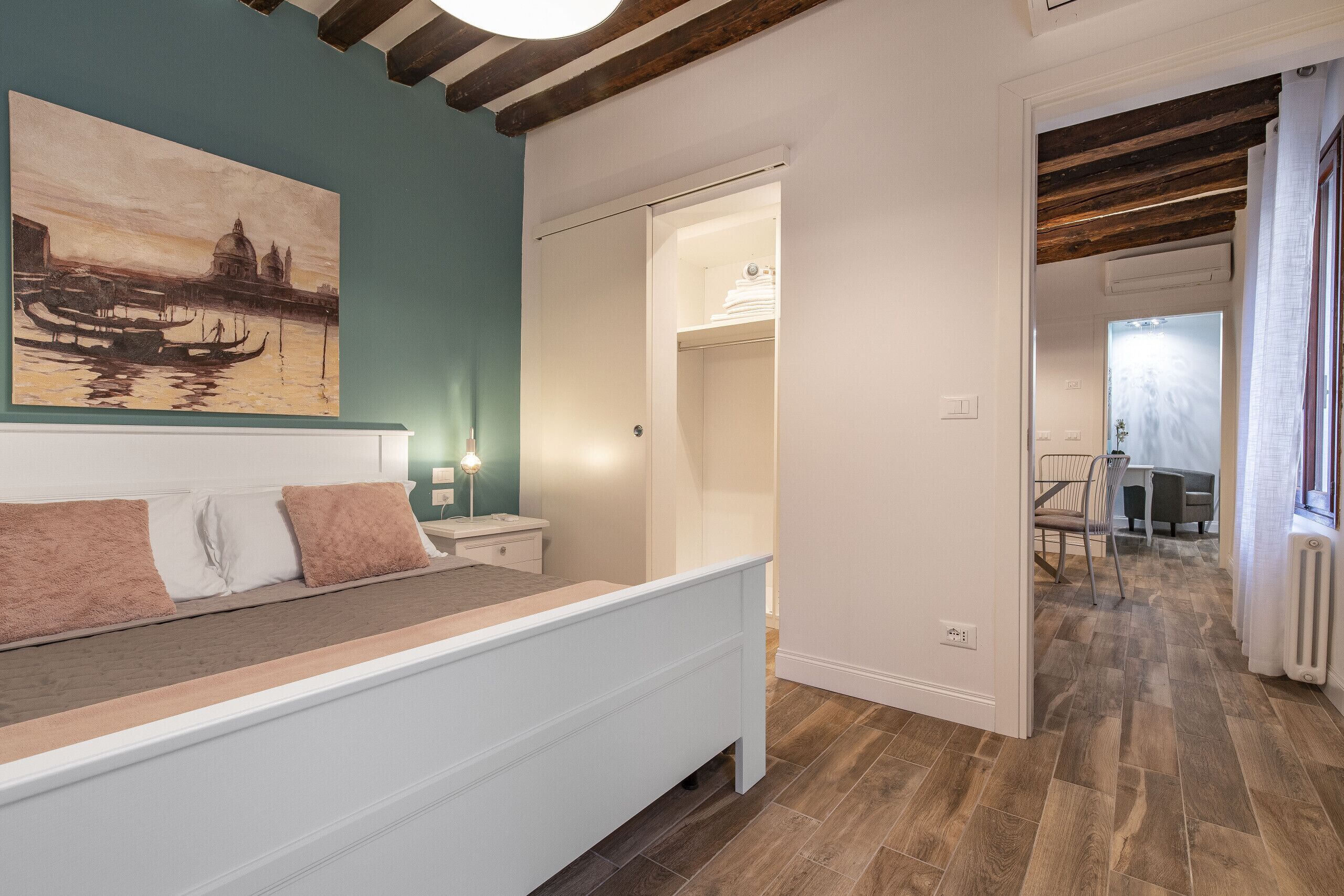 Ein Schlafzimmer mit einem Bett, einem Bild an der Wand und Holzboden.