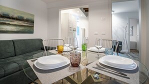 Un espace repas avec une table en verre, des chaises et des assiettes.