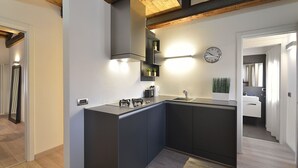 A modern kitchen with a built-in island, a gas stove, and a sink. There is a clock on the wall and a plant on the counter. - Skyline Penthouse by Wonderful Italy (Venecia)