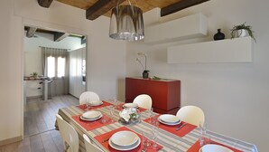 A dining area with a table set for four, a red cabinet, and a hanging light fixture. - Skyline Penthouse by Wonderful Italy (Venecia)