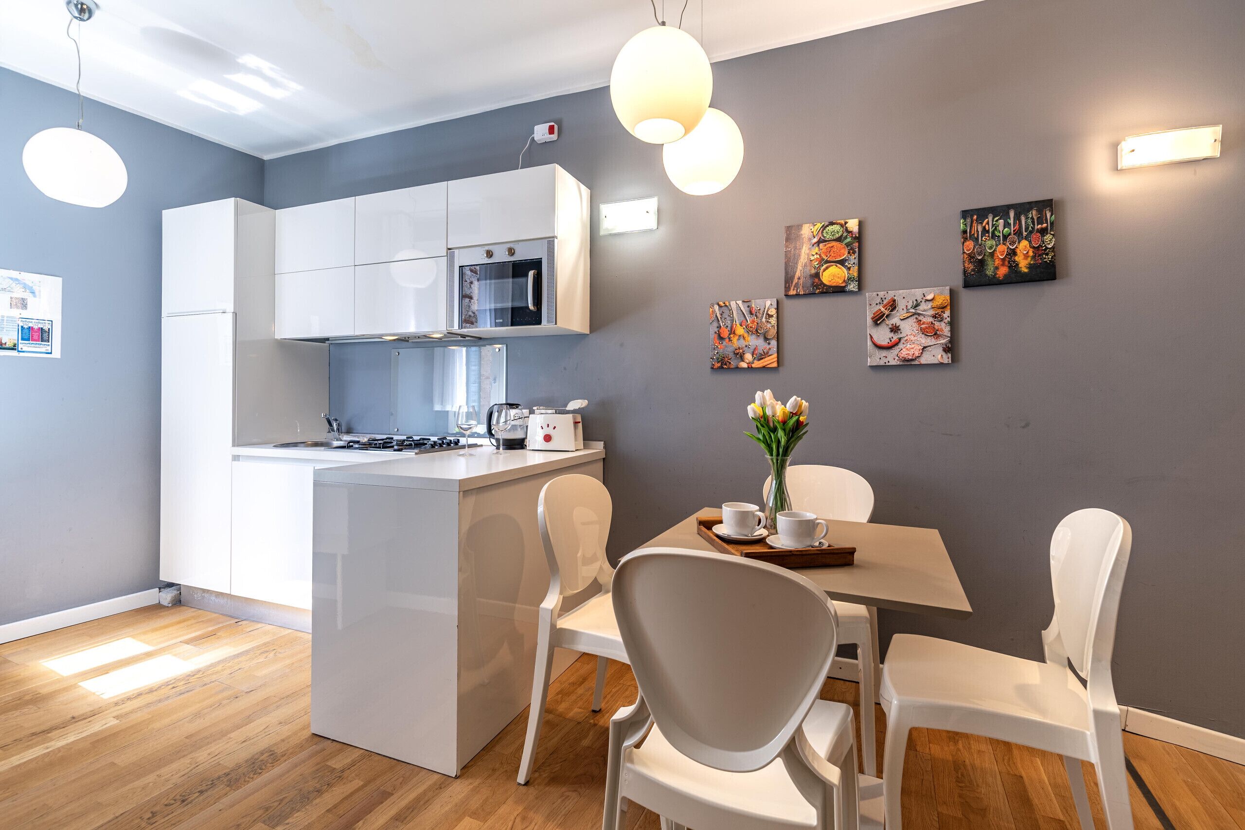 Una cocina moderna con armarios blancos, horno empotrado y comedor con mesa y sillas.