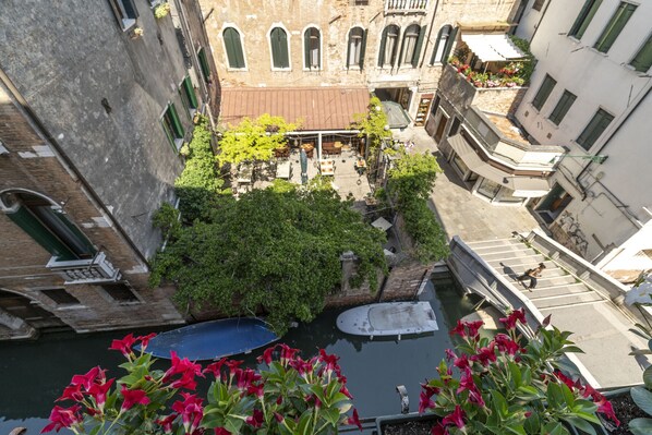 A narrow Venetian canal with boats, surrounded by historic buildings with arched windows and balconies.
