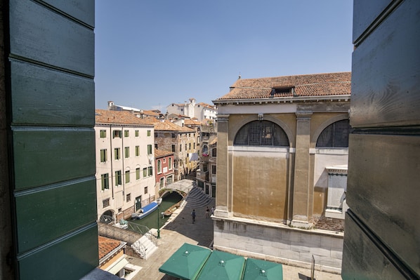 A view of a narrow Venetian street with buildings, a canal, and a bridge.