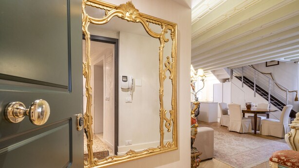 Una habitación con un espejo grande y ornamentado, una escalera y un comedor.