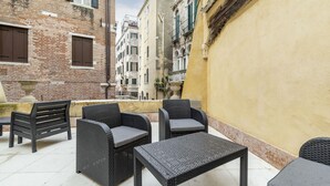 Un patio exterior con muebles de mimbre y vistas a edificios históricos.