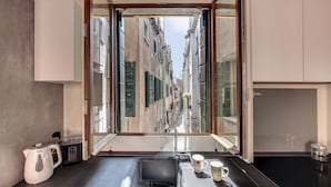 A modern kitchen with a large window, a kettle, a coffee maker, and a tray with cups. - Rugabella Rialto by Wonderful Italy (Venecia)