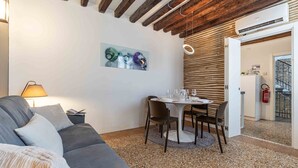Un soggiorno moderno con un divano grigio, un tavolo da pranzo con sedie, un quadro appeso al muro e un soffitto in legno.