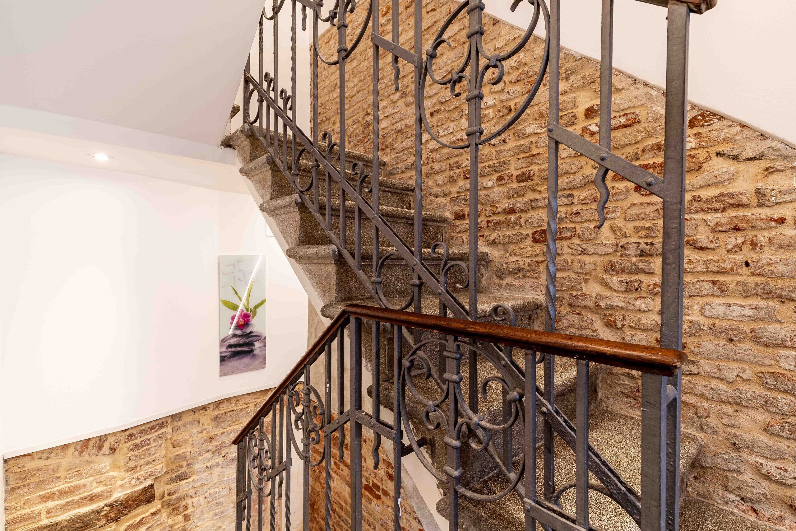 Una escalera con barandales de hierro forjado y un muro de piedra.