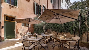 Un patio al aire libre con mesas, sillas, sombrillas y un edificio al fondo.