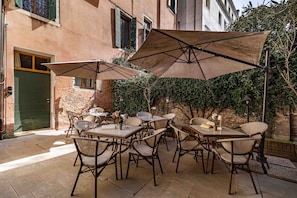 Un patio al aire libre con mesas, sillas, sombrillas y un edificio al fondo.