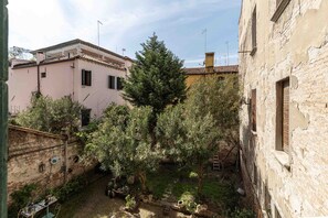 Um pátio com edifícios, árvores e um muro de tijolos.