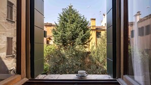 Una ventana con una taza en el alféizar, un árbol y edificios al fondo.