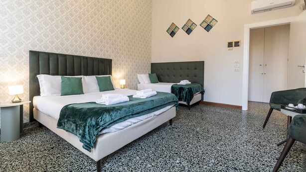 Ein Hotelzimmer mit zwei Betten, einer Chandelüster, einer Klimaanlage und einer Wand mit Muster.
