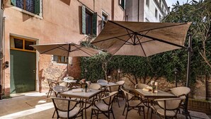 Un patio al aire libre con mesas, sillas, sombrillas y un edificio al fondo.