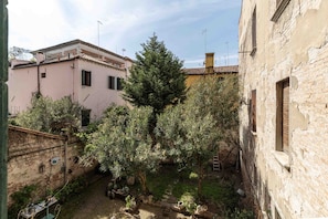 A courtyard with buildings, trees, and a brick wall. - Centopietre by Wonderful Italy - Camera Blue Moon (Venecia)