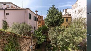 Un estrecho callejón flanqueado por edificios, un árbol y una pequeña zona de estar al aire libre.