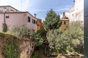 Une ruelle étroite, bordée de bâtiments des deux côtés, avec un arbre et un petit espace aménagé pour s’asseoir à l’extérieur.