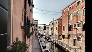 A narrow canal with boats docked along the sides, flanked by historic buildings with visible balconies and windows.