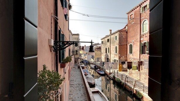 A narrow canal with boats, buildings on either side, and a staircase leading down.