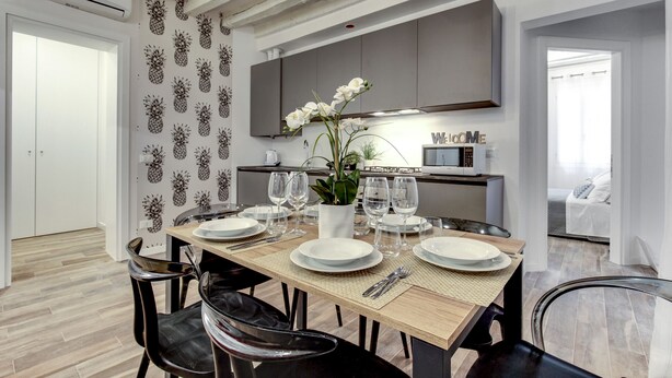 A modern dining area with a wooden table set for four, surrounded by black chairs. - Laguna Luxury 2 by Wonderful Italy (Venecia)
