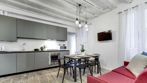 A modern kitchen with grey cabinets, a dining table with chairs, a red sofa, and a TV on the wall. - Laguna Luxury 2 by Wonderful Italy (Venecia)