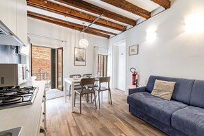 Een moderne keuken met een gasfornuis, een eettafel met stoelen, een blauwe bank en een houten plafond.