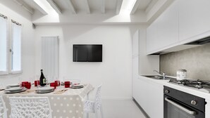 A modern kitchen with white cabinetry, a built-in oven, and a flat-screen TV mounted on the wall. - Bellini Design by Wonderful Italy (Venecia)