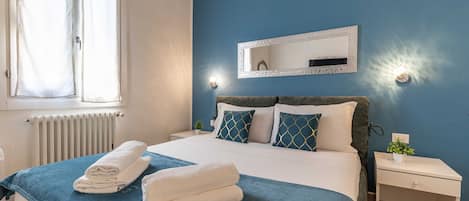 Una camera da letto con un letto, un comodino, uno specchio e una finestra con tende.