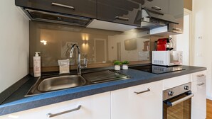 Una cocina moderna con un lavamanos de acero inoxidable, horno empotrado y microondas.