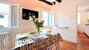 Ein Essbereich mit einem Tisch für vier Personen, einer Blumenvase und einem Fernseher an der Wand.