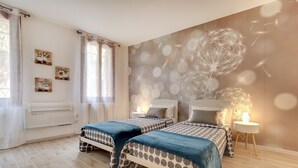 Une chambre avec deux lits, une peinture murale et une fenêtre avec des rideaux.