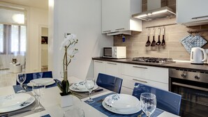 Une cuisine moderne avec des meubles blancs, un four à micro-ondes, une cuisinière à gaz et des ustensiles suspendus.