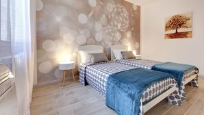 Une chambre avec deux lits, une peinture murale et un tableau.